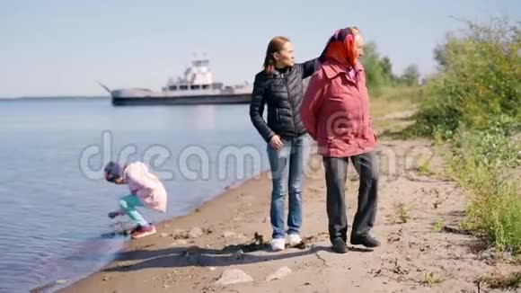 一位年迈的妇女带着一个成年的女儿和孙女沿着海岸散步在一个人身上愉快地交谈和大笑视频的预览图