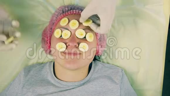 化妆师的男人的手从女人的脸上摘下香蕉上的面具从上面看视频的预览图