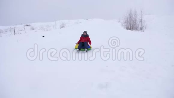 快乐的年轻女孩从大雪中滑出一个充气的雪管孩子们冬天在公园里玩圣诞节视频的预览图