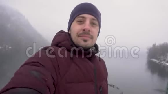 快乐旅行人自拍并展示阿布哈兹里萨湖冬天的雪天视频的预览图