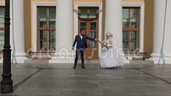 快乐的新婚夫妇在公园的柱子上跳舞视频的预览图