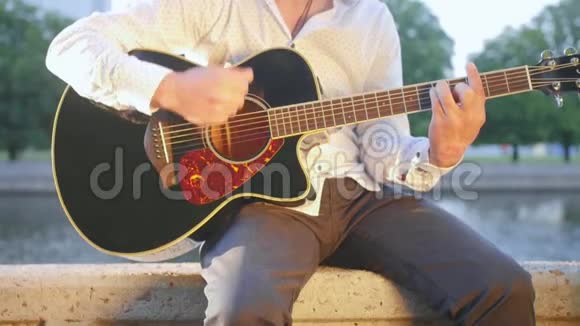 人坐在公园里的石砌木板路上弹吉他近距离射击视频的预览图