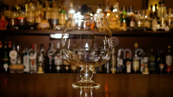 热葡萄酒倒入一个大玻璃杯的背景上的酒吧橱柜与瓶子煮木果酒视频的预览图