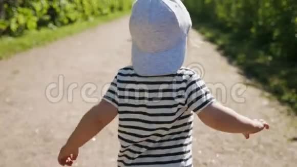 穿着帽子和t恤的小男孩在街上奔跑视频的预览图