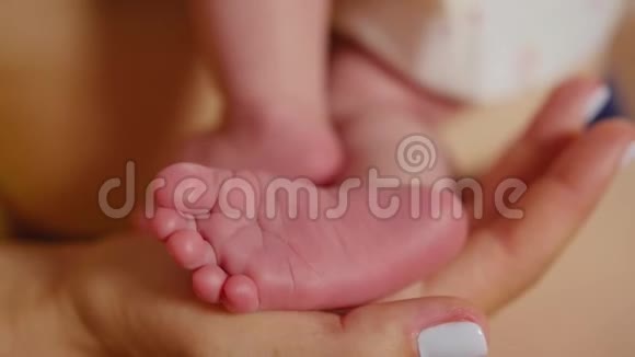 宝宝的脚在妈妈手里微小的新生婴儿的脚在女性心形的手特写妈妈和她的孩子快乐视频的预览图