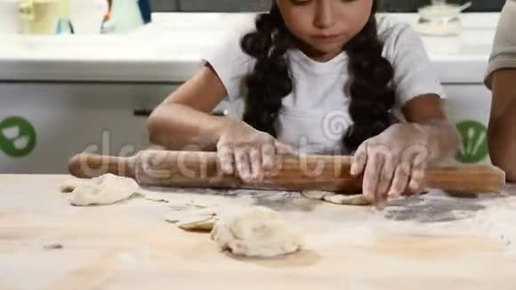 孩子面包店可爱的女孩戴着厨师帽在厨房的桌子上擀面团小厨师准备蛋糕4k视频的预览图