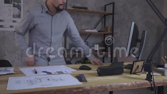 那个人坐在桌子旁开始用电脑工作旁边是图纸视频的预览图