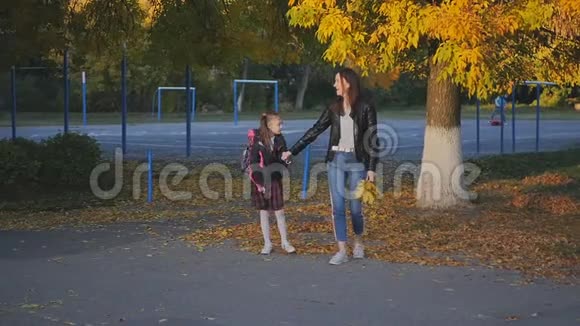 快乐的母亲带着女儿穿着校服回家妈妈和女儿谈笑风生缓慢运动日落视频的预览图