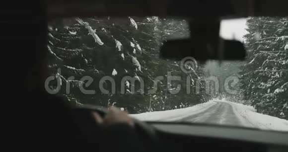 一个男子骑在汽车的车轮后面在白雪覆盖的山路4K超高清视频的预览图