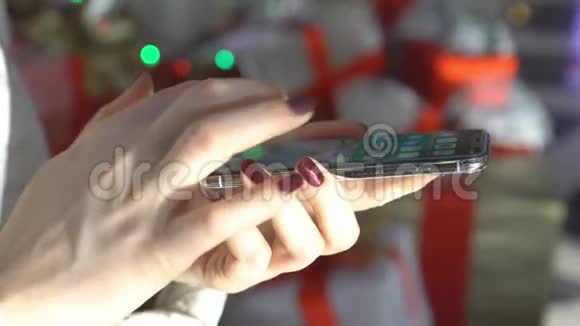 特写镜头在购物中心拿着智能手机的女人的手圣诞节太阳光斑的反射视频的预览图