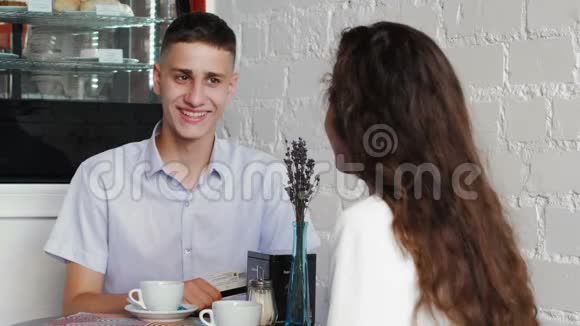 穿蓝色衬衫的人在咖啡馆里用NFCTehnology的卡片付账一对年轻夫妇在咖啡馆的约会视频的预览图
