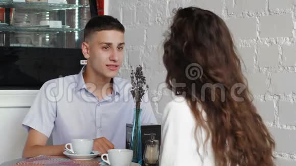 穿蓝色衬衫的人在咖啡馆里用手表付账一对年轻夫妇在咖啡馆的约会视频的预览图