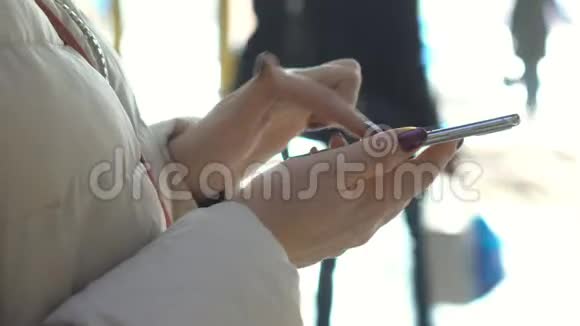 特写镜头在购物中心拿着智能手机的女人的手圣诞节太阳光斑的反射视频的预览图