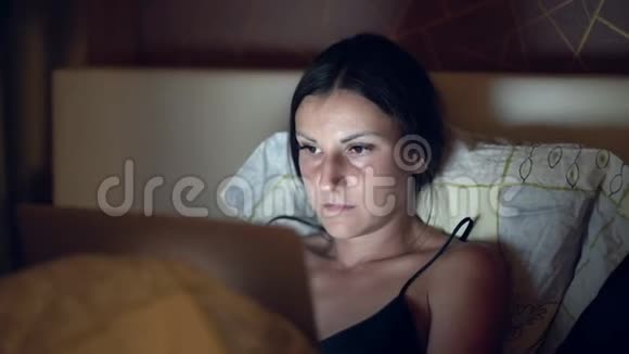 躺在床上工作的女人晚上在床上用电脑工作的女孩视频的预览图