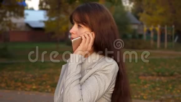 晚上女孩在公园里用手机说话手里拿着黑色公文包视频的预览图