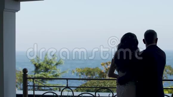 后景新郎拥抱新娘他们从阳台看大海视频的预览图