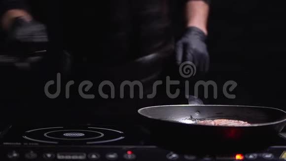 穿着黑衣服和手套的厨师在现代化的电炉上为汉堡准备肉视频的预览图