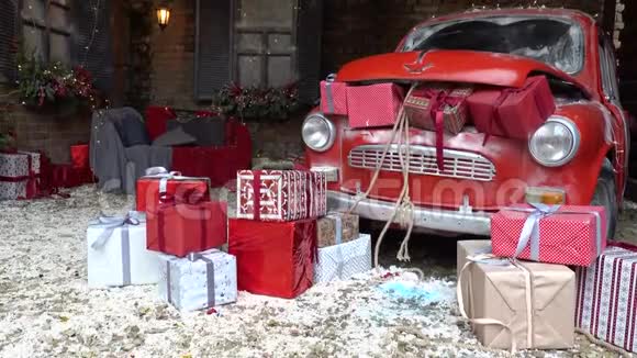 新年装饰的外部装有圣诞礼物的后备箱复古的红色汽车雪和节日灯和视频的预览图