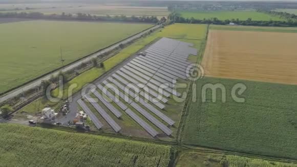 在日落时用太阳能电池板在绿色的田野里绕着田野飞行太阳能电池板清洁可再生能源视频的预览图