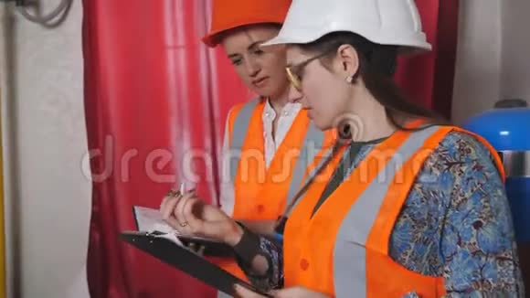两名女工程师检查锅炉房供暖系统设备的技术数据视频的预览图