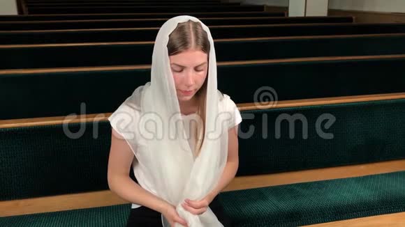 在浸信会教堂祈祷的年轻虔诚的妇女欧洲大教堂虔诚的天主教徒圣地内部视频的预览图