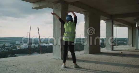 漂亮的年轻女子穿着安全装备在建筑工地的屋顶上跳舞视频的预览图