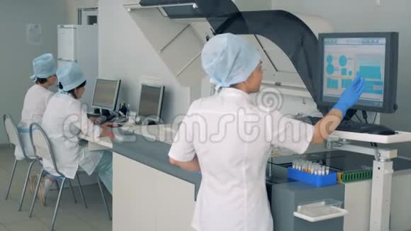 女实验室专家正在一家药品工厂的触摸屏上操作生化分析仪视频的预览图