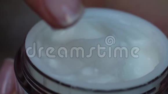 手指从瓶子里拿一些奶油护肤卫生和健康的生活理念关门视频的预览图
