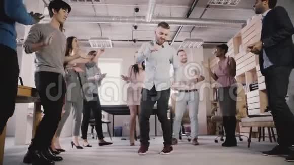 令人兴奋的多民族商务人士在办公室团队建设聚会上围圈跳舞庆祝成就慢动作视频的预览图