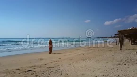 女人拿着冲浪板在蓝天下对抗海浪视频的预览图