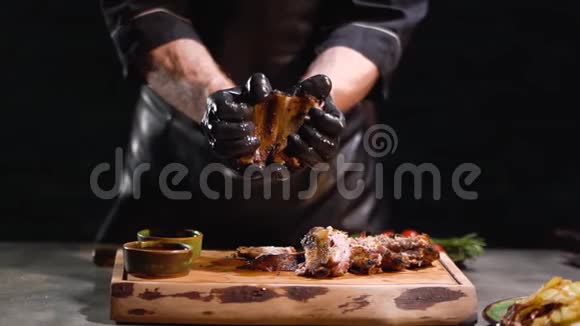 穿着黑色橡胶手套的男性双手撕裂美味的烤肋骨慢动作视频的预览图
