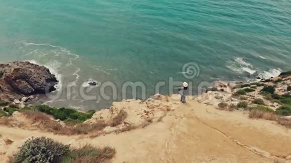 孤独的女人站在悬崖上看海景视频的预览图