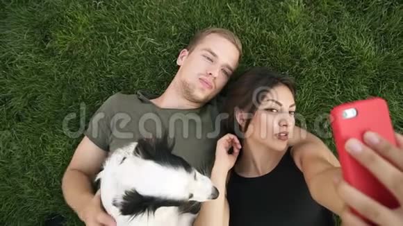 年轻有魅力的白种人夫妇躺在公园的绿草上男人抱着他们的小黑白视频的预览图