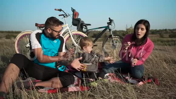 一对已婚夫妇骑着自行车带着一个孩子肥皂泡和乐趣视频的预览图