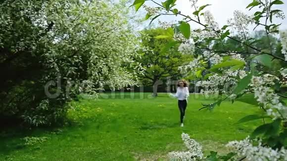 美丽的欧洲女孩长发奔跑和嗅一个盛开的鸟樱桃慢动作视频的预览图