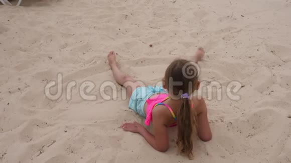 小女孩躺在沙滩上做蝴蝶腿踩着沙子视频的预览图