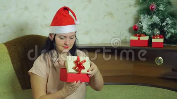 一个戴着圣诞老人帽子的女人用仿雪装饰圣诞树视频的预览图