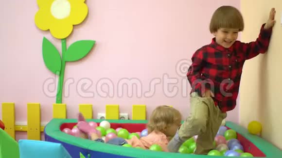 可爱的白种人学龄前幼儿在多种颜色的球池中玩耍托儿所视频的预览图