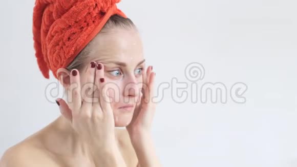 美丽的女人在她的脸上涂上保湿霜面对关怀视频的预览图
