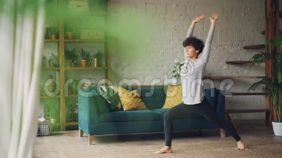 穿运动服的瘦小女子在家训练独自站在地板上练习瑜伽视频的预览图