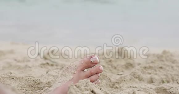 在海边的沙滩上用漂亮的脚趾甲特写一条女腿视频的预览图