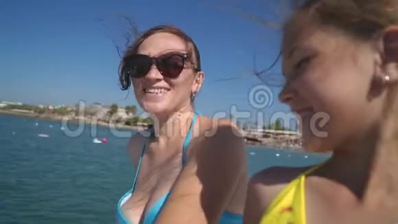 快乐的女孩和她的母亲在船上航行到岸边视频的预览图