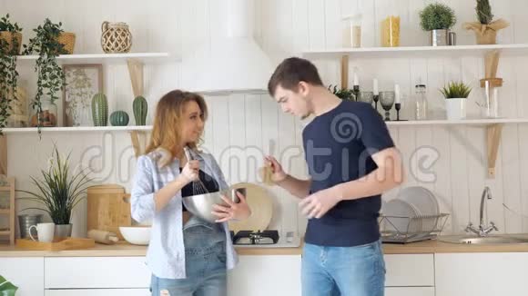 金发女人把食物倒在碗里男人在厨房品尝视频的预览图