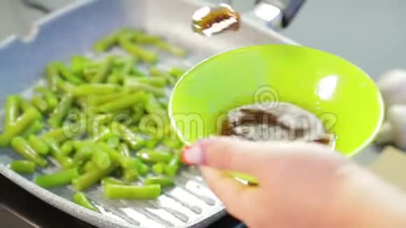 在平底锅中绿色的串豆被磨成油用木铲搅拌视频的预览图