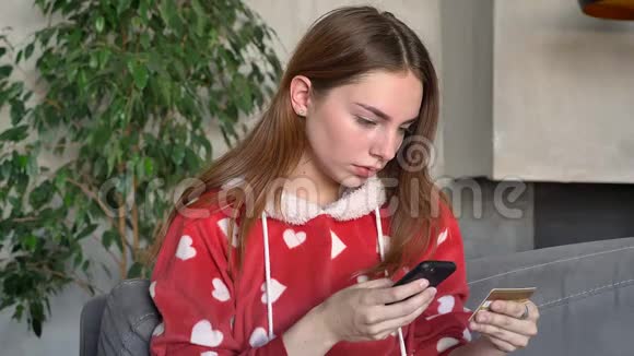 美丽的姜女用手机上的信用卡拿着智能手机打字在网上购物视频的预览图