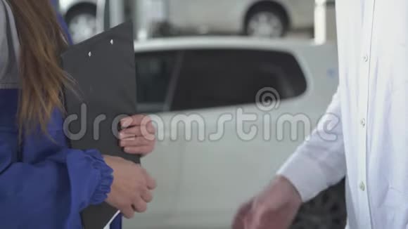 女汽车专家在拍了有关汽车的数据后签了名拿起钥匙和握手视频的预览图