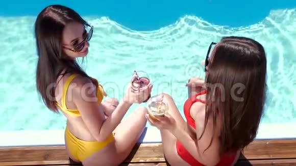 两个女孩坐在游泳池旁边视频的预览图
