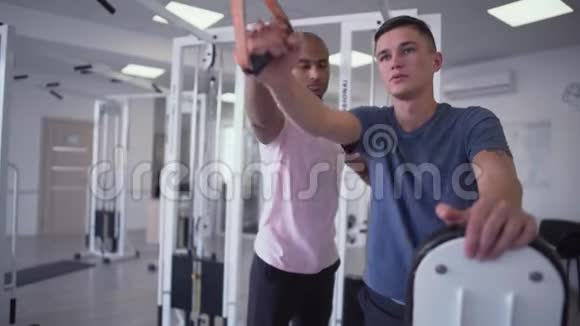 非裔美国人教练帮助年轻人训练健身房里的人视频的预览图