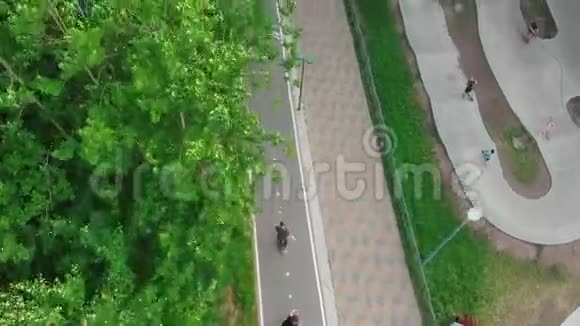 年轻人在绿色现代公园的特殊道路上滑板视频的预览图