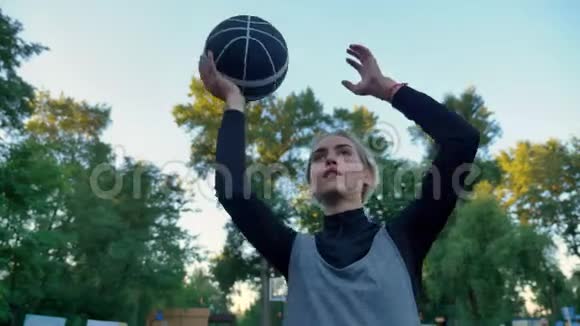 漂亮的女篮球运动员扔球在公园里玩蓝天低角度视频的预览图